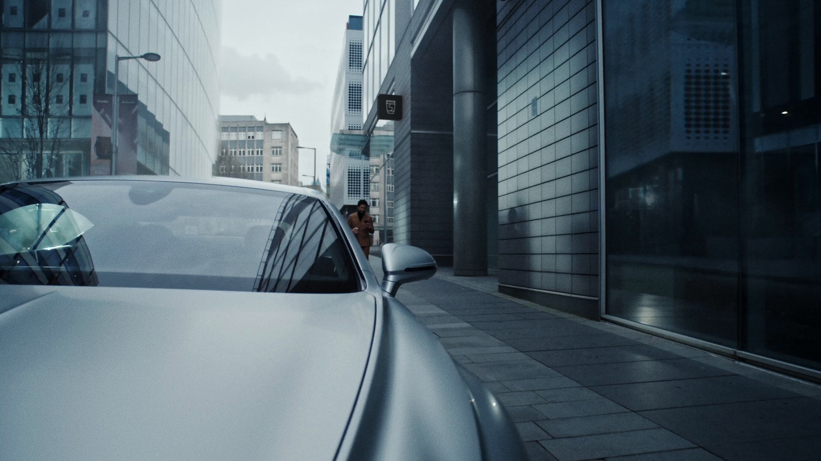 a car parked on the side of a street next to tall buildings