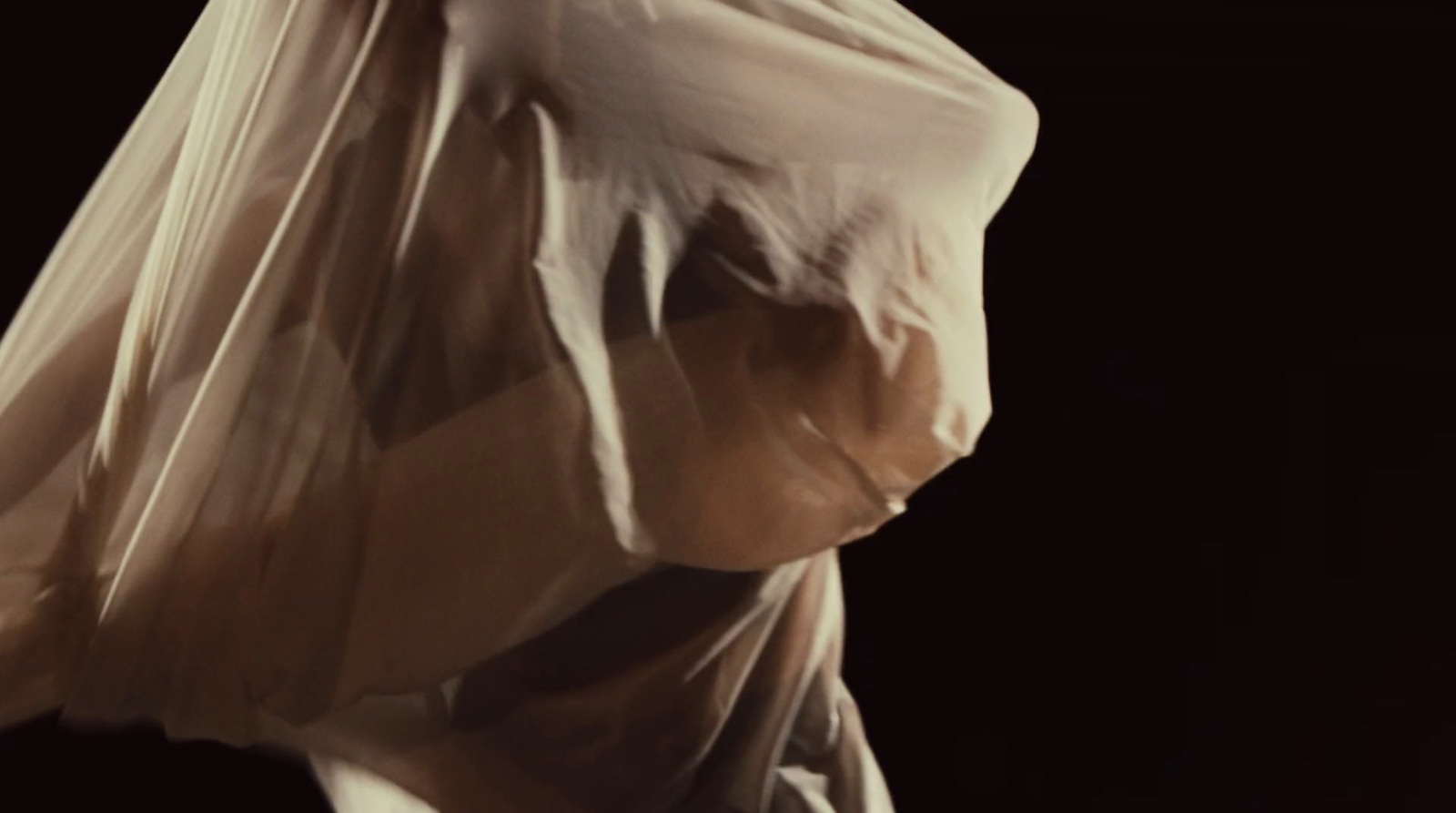 a woman wrapped in a plastic bag in the dark