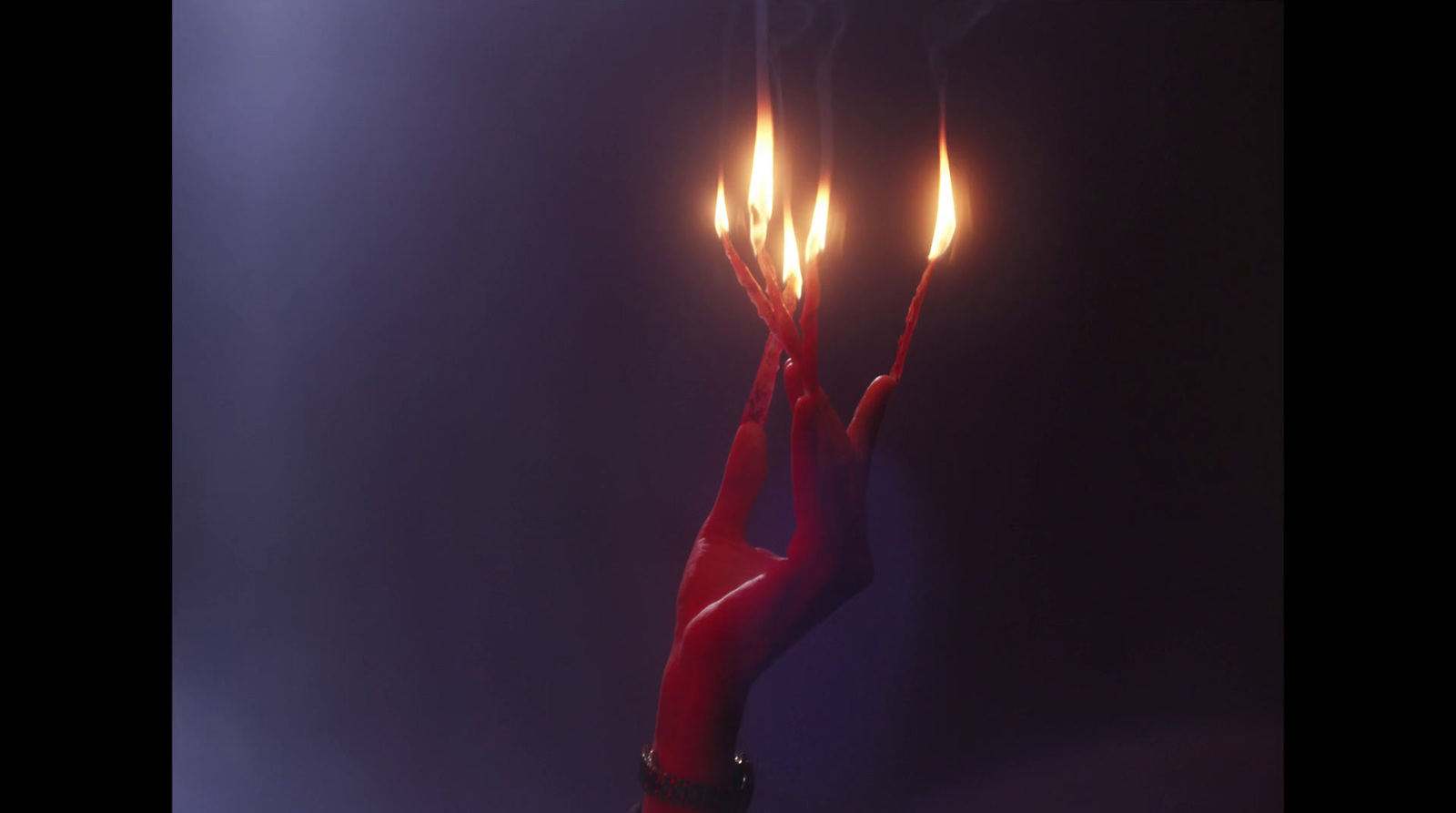 a hand holding a lit candle in the dark