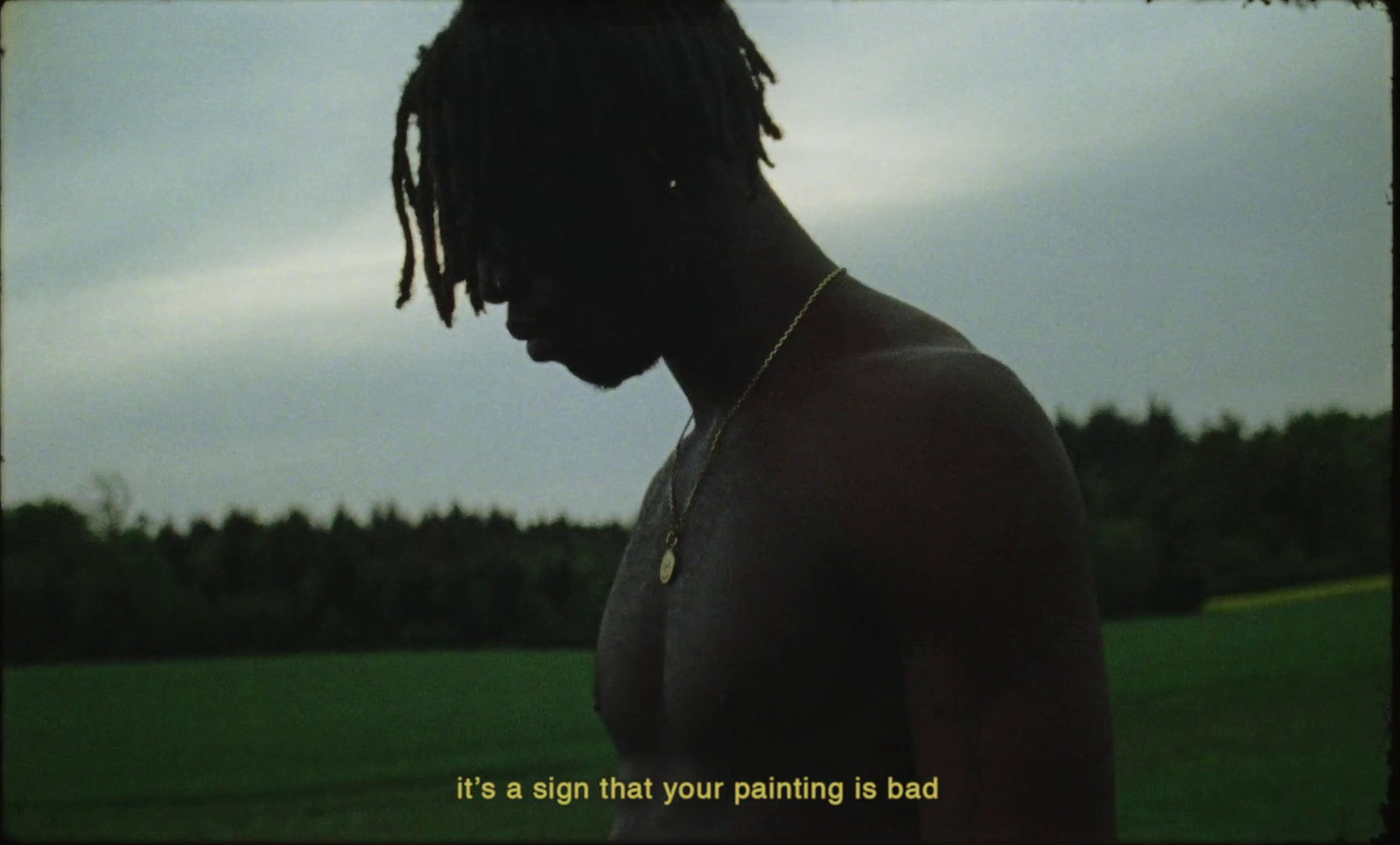 a man with dreadlocks standing in a field