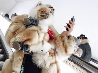 a woman in a fur coat holding a cell phone