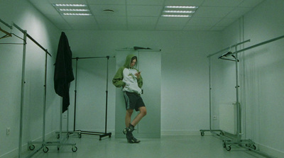 a man standing in a white room with a green hoodie