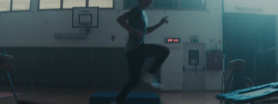 a man standing on top of a blue box in a gym