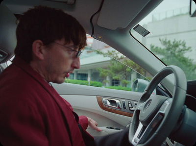 a man in a red shirt driving a car