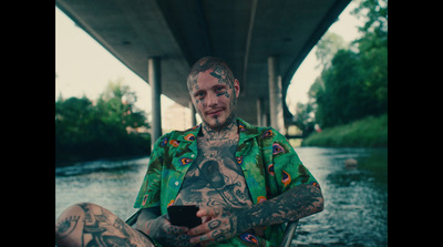 a man with tattoos sitting under a bridge