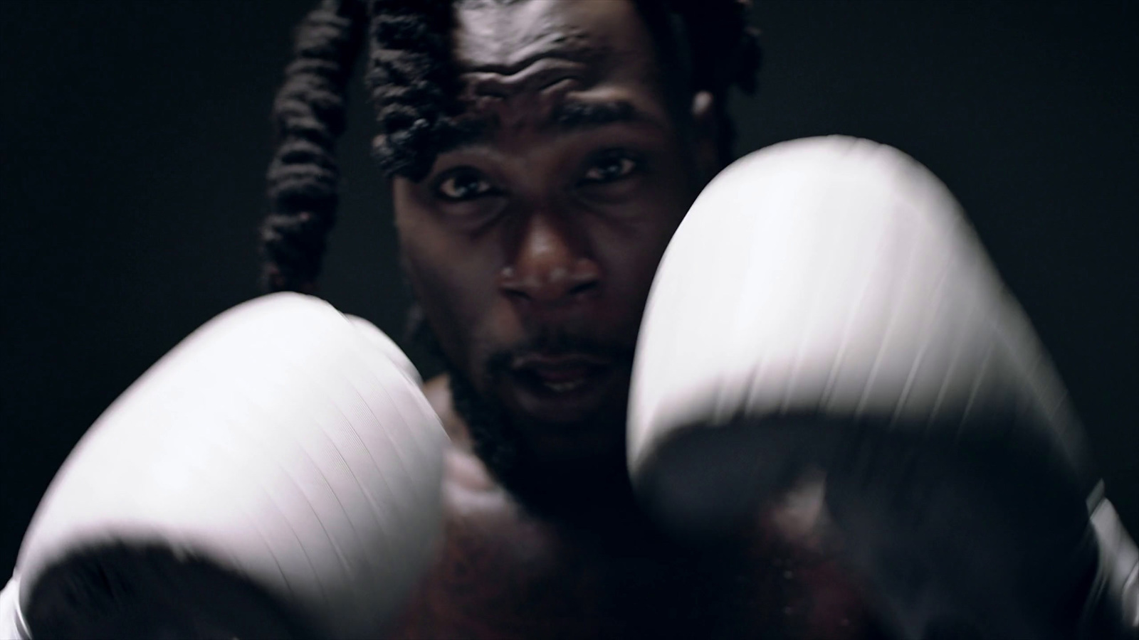 a man with dreadlocks holding a pair of boxing gloves