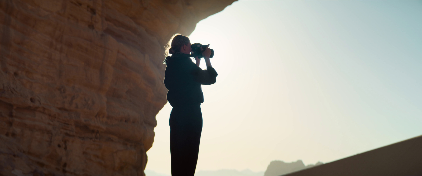 a woman taking a picture of a cliff with a camera