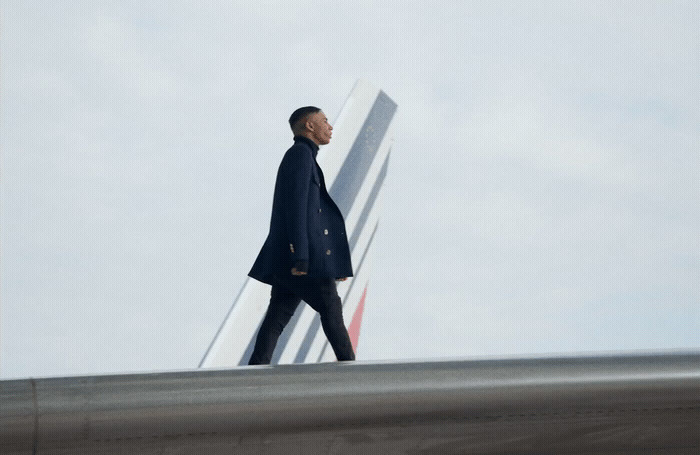 a man in a blue coat walking on a runway