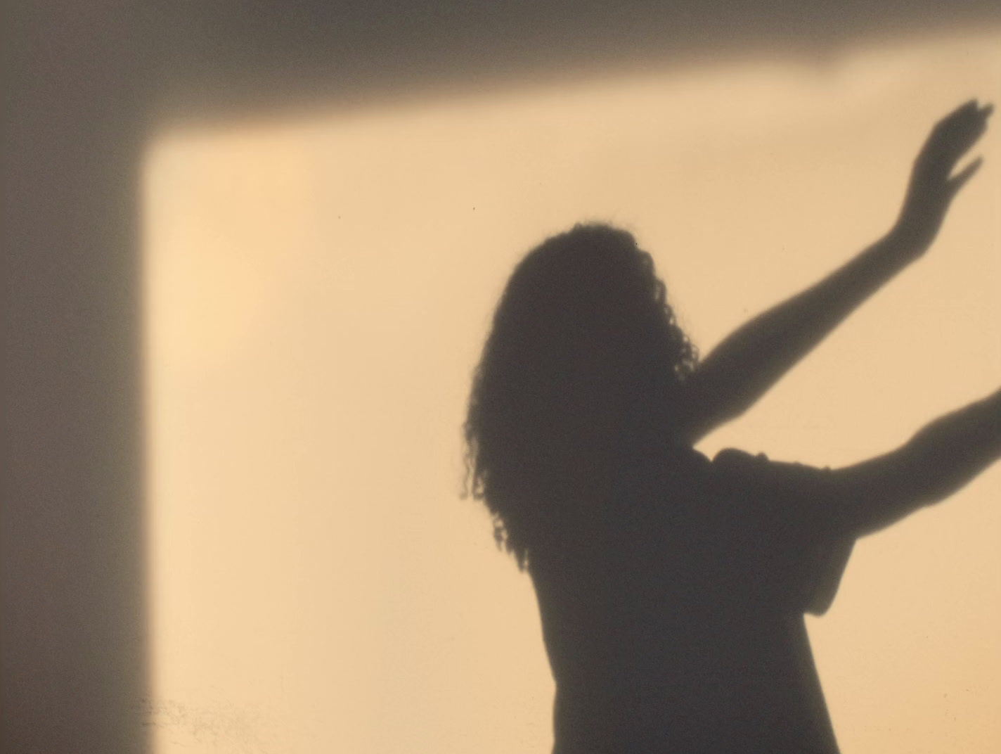 a woman standing in front of a window with her arms outstretched