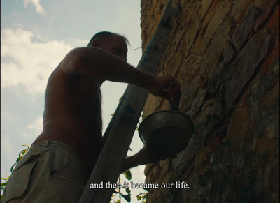 a man holding a bucket up against a stone wall