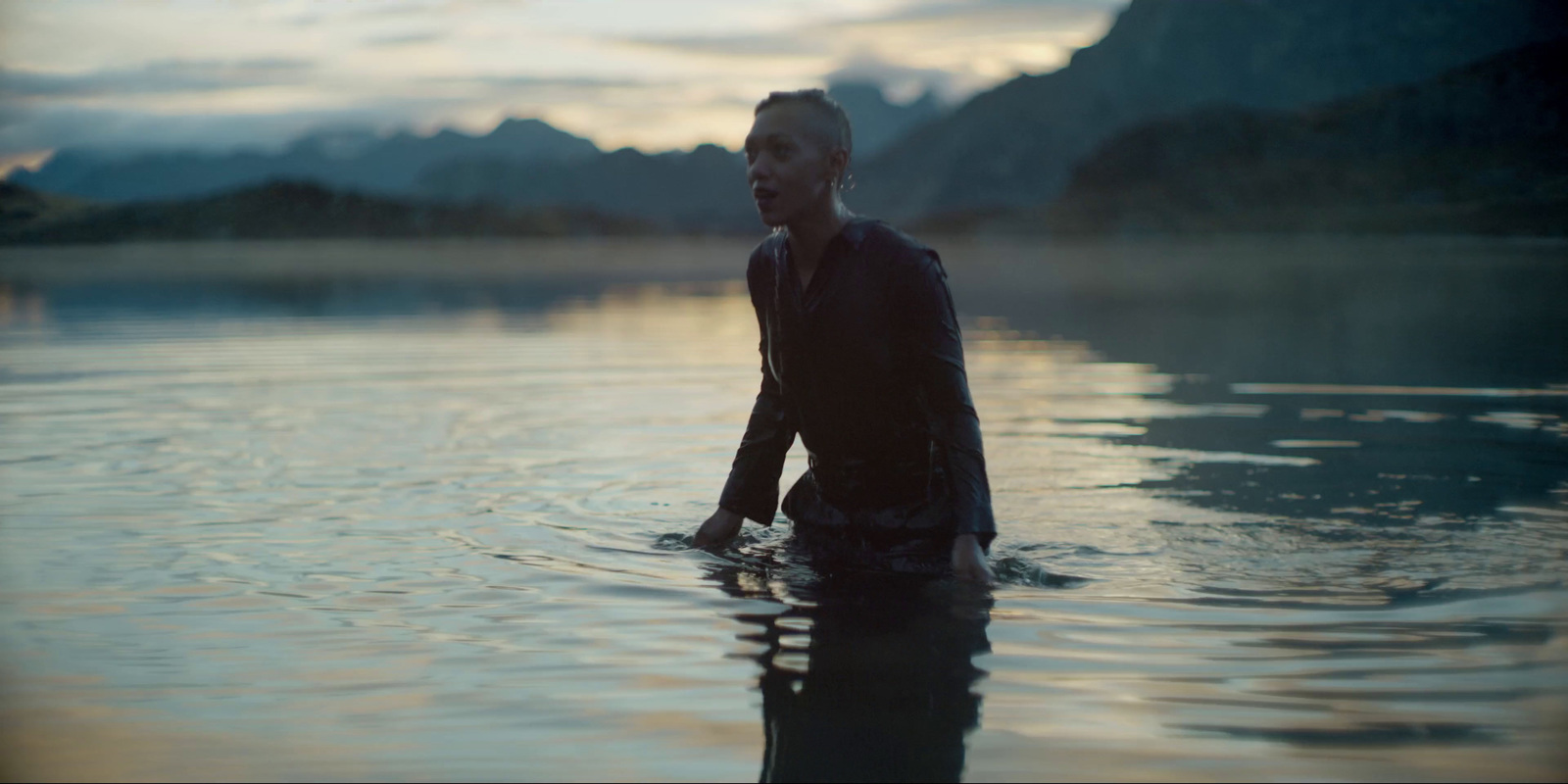 a man is wading in the water at sunset