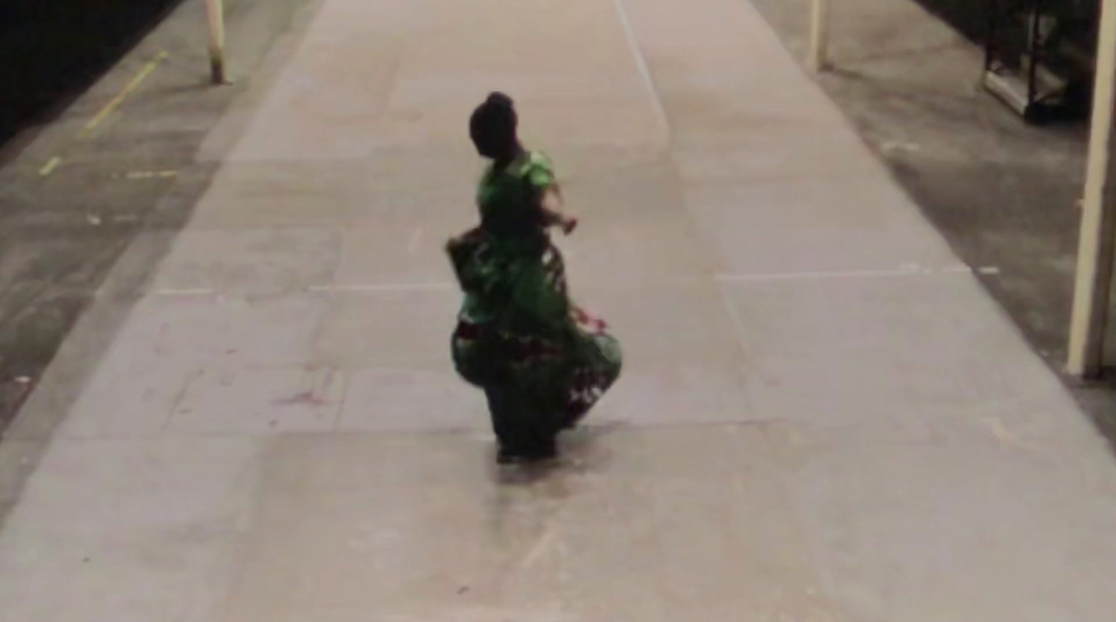 a woman in a green dress walking down a sidewalk