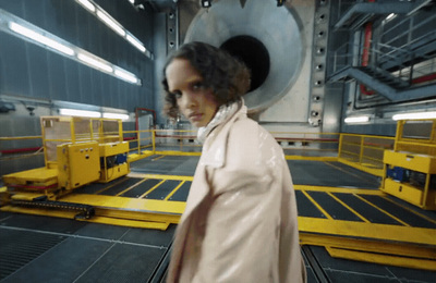 a woman in a white coat standing in front of a machine