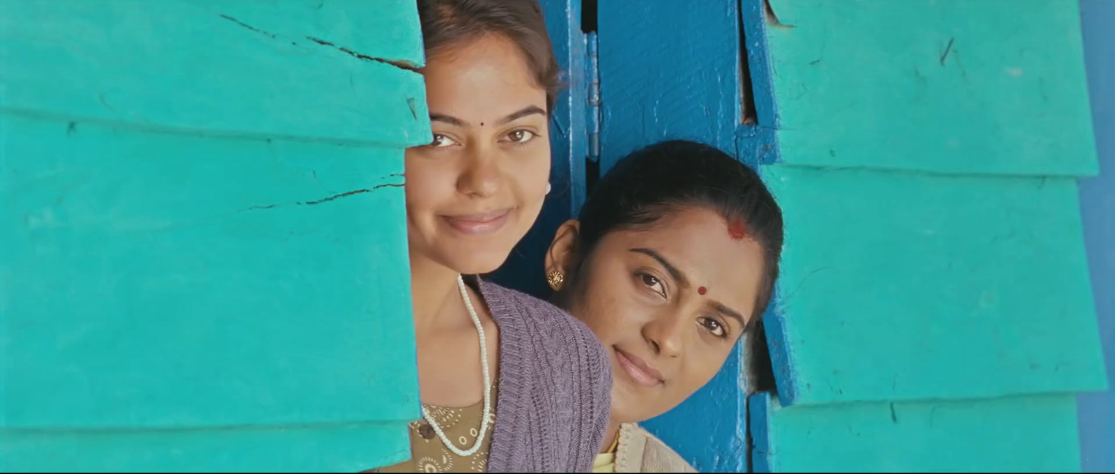 two women standing next to each other in front of a blue wall