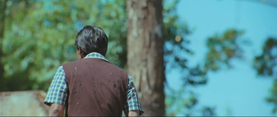 a man in a vest walking through a forest