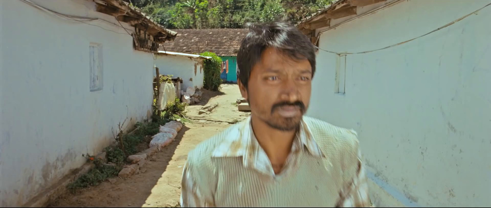 a man with a mustache standing in an alley way