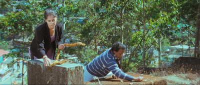 a man and a woman are working on a piece of wood