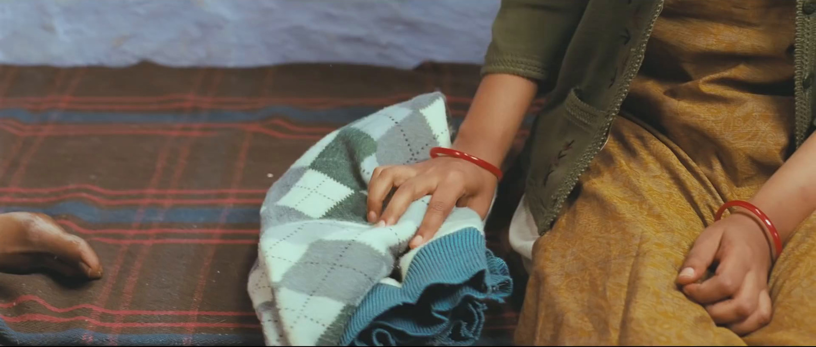 a woman sitting on the ground with her hand on a blanket