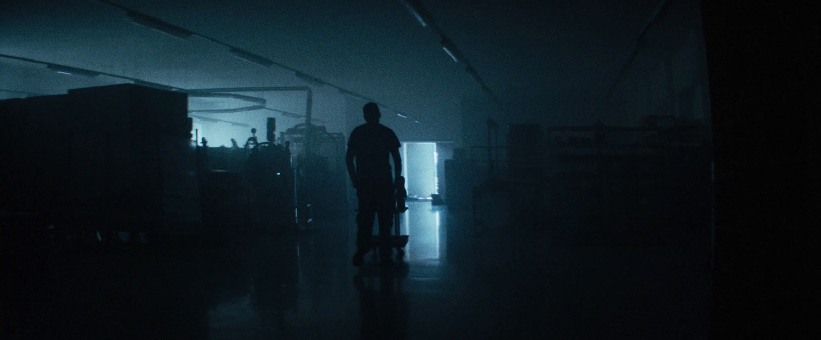 a man standing in a dark room with a suitcase