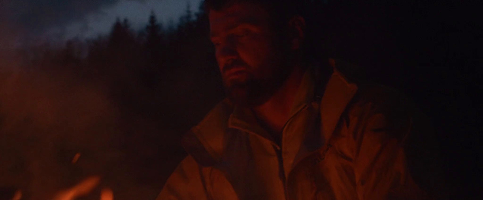 a man standing in front of a fire in the dark