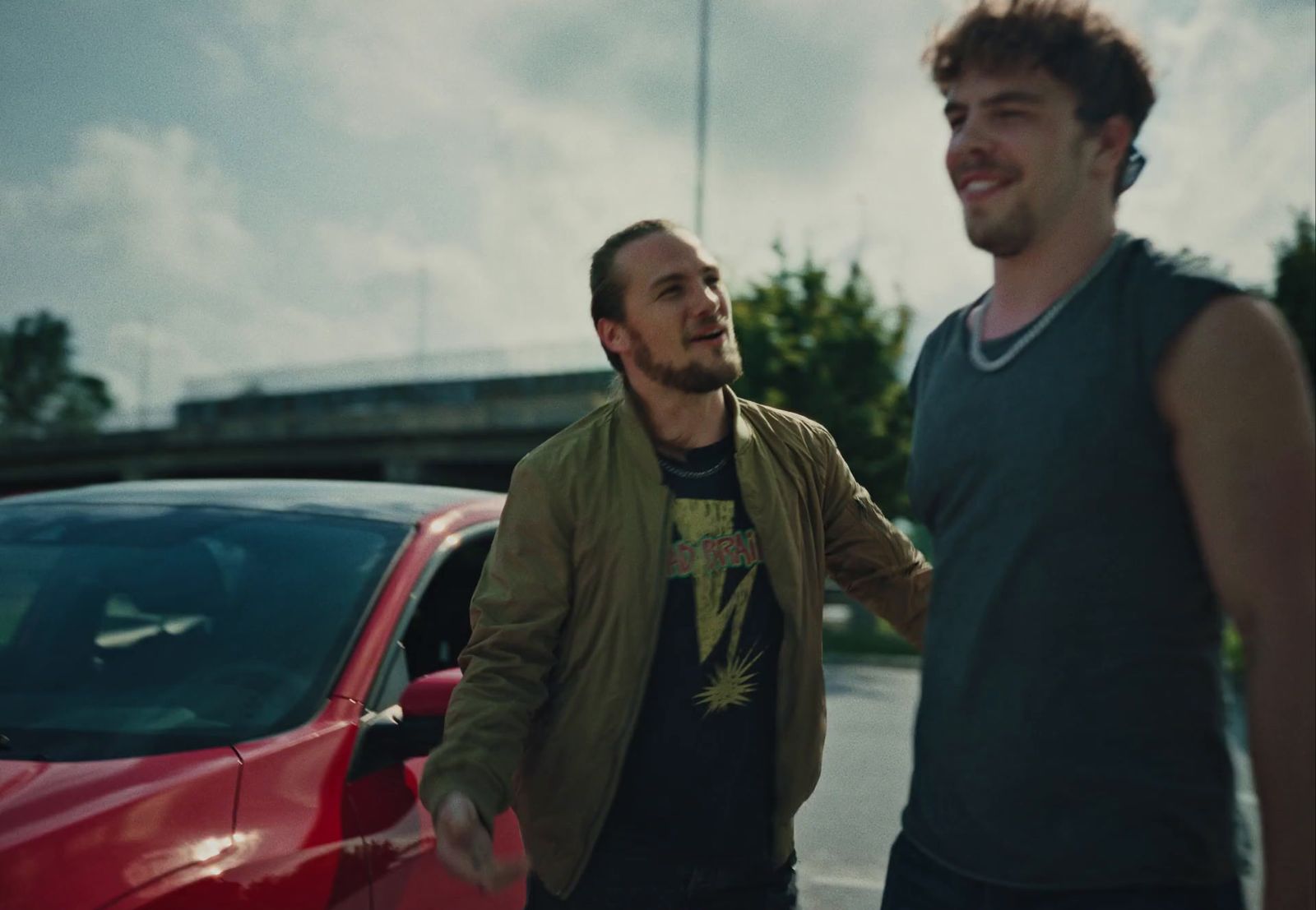 a couple of men standing next to a red car