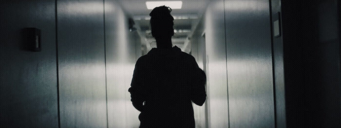 a man standing in a dark hallway with his back to the camera