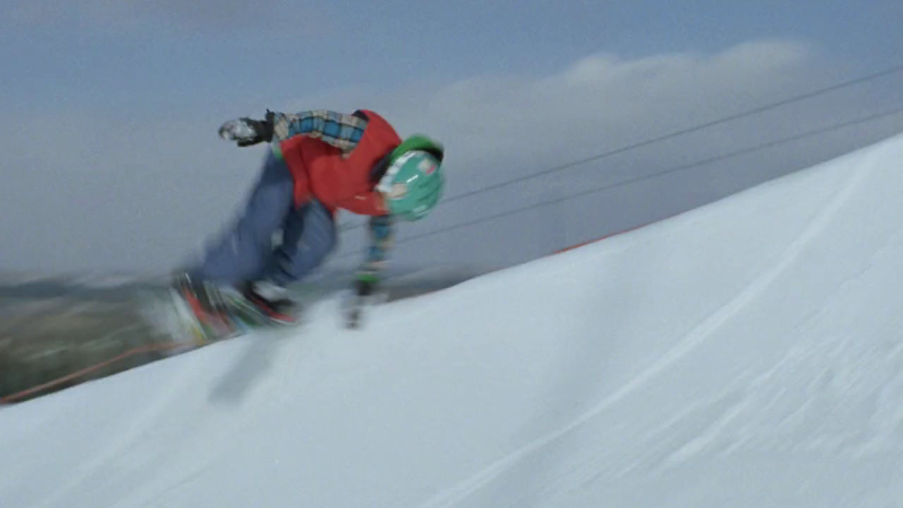 a man riding a snowboard down the side of a snow covered slope