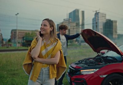 a woman talking on a cell phone next to a car