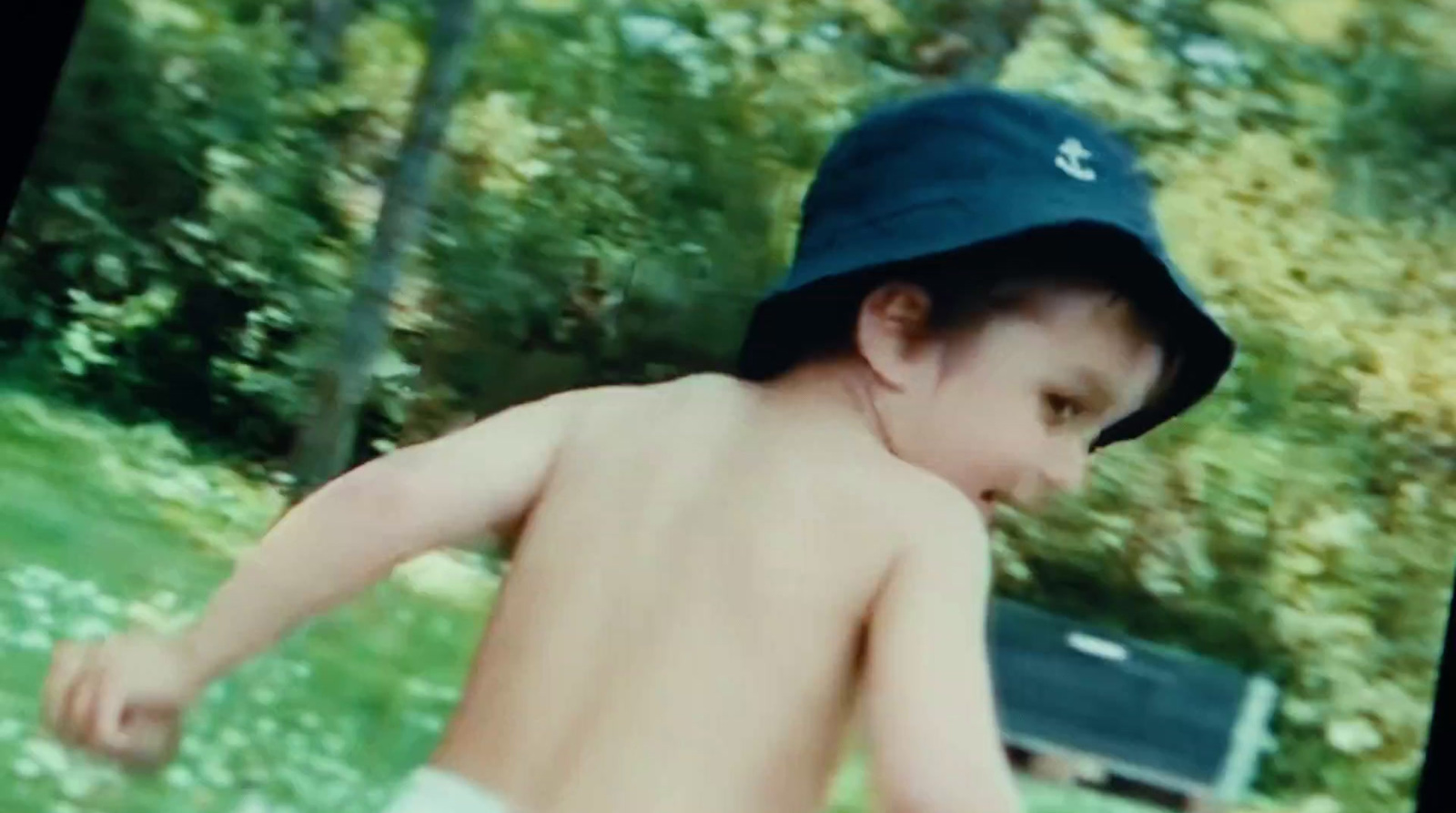 a young boy wearing a blue hat running in the grass