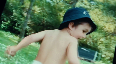 a young boy wearing a blue hat running in the grass