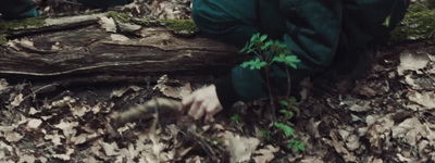 a person in a green jacket crouching on the ground