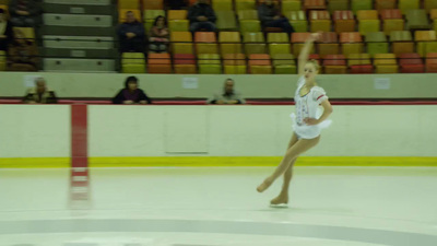 a woman in a white leotard skating on an ice rink