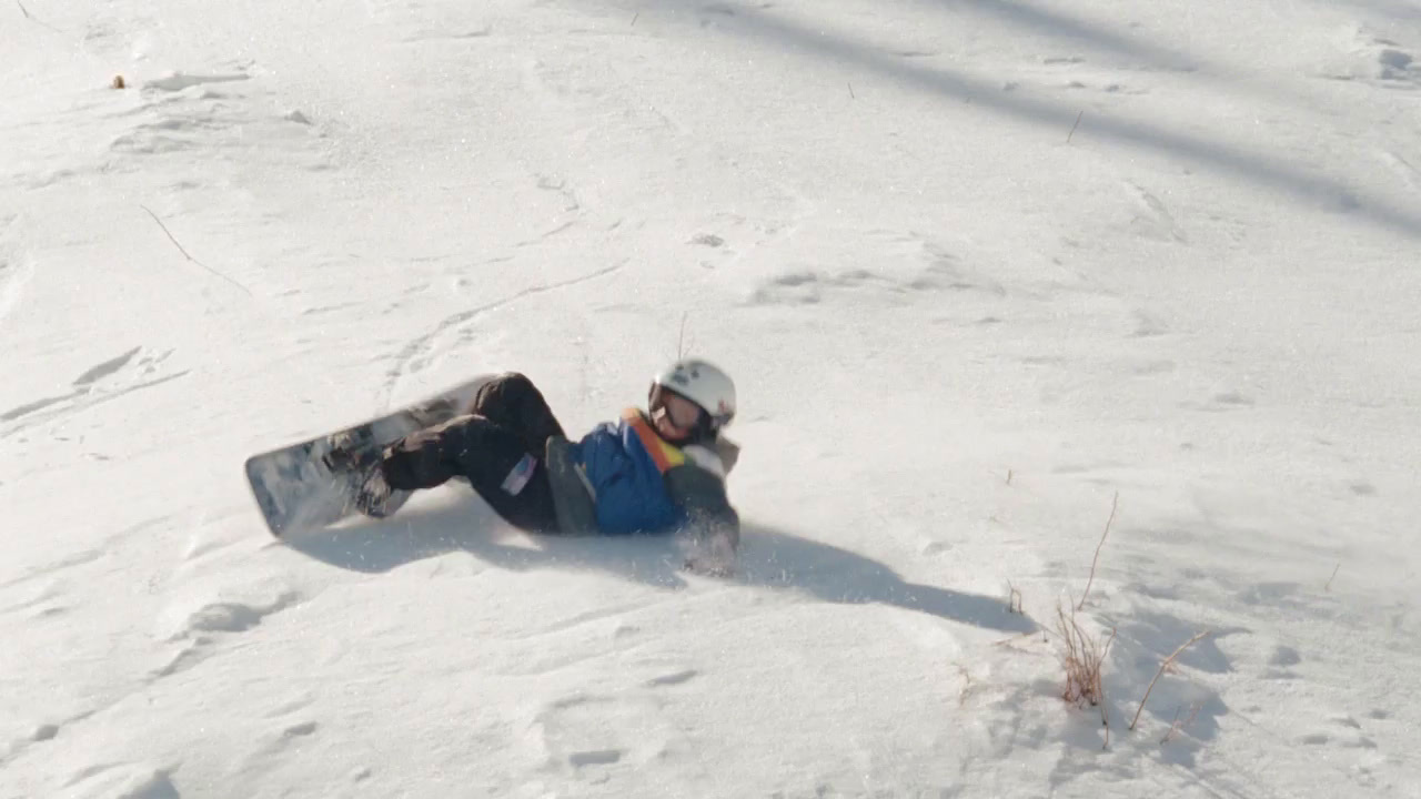 a snowboarder laying on the ground in the snow