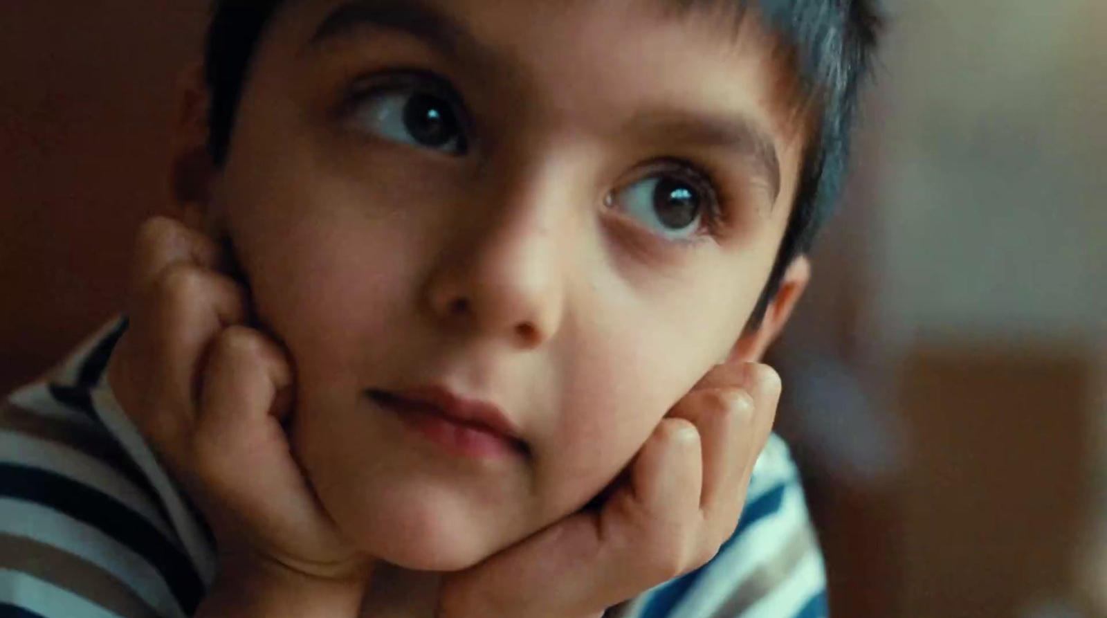 a young boy with blue eyes and a striped shirt