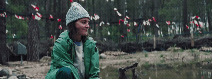 a woman sitting on a log in a forest