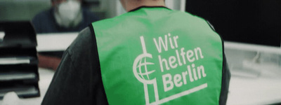 a man wearing a green vest with a white logo on it