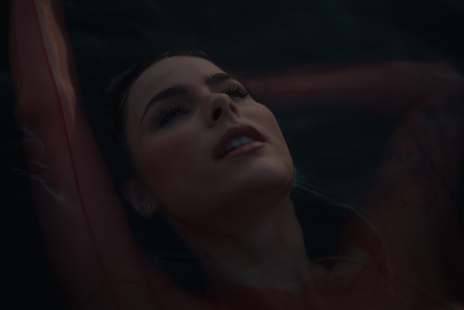 a woman laying down in the water with her eyes closed