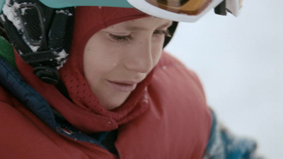 a woman in a red jacket wearing a snowboard helmet