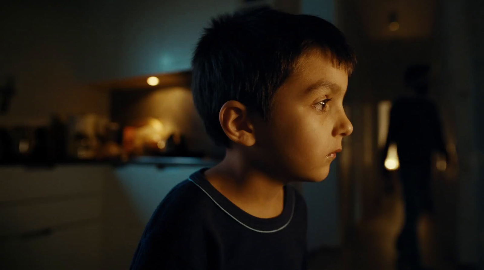 a young boy standing in a kitchen at night