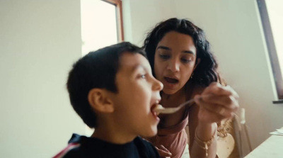 a woman feeding a boy with a spoon