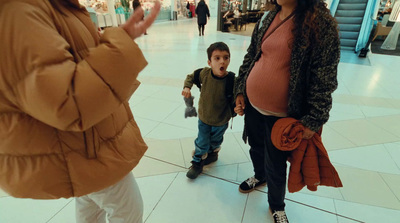 a woman standing next to a little boy in a mall