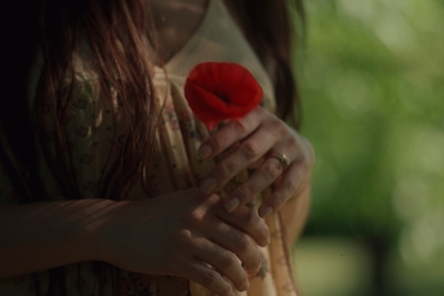 a woman holding a red flower in her hands