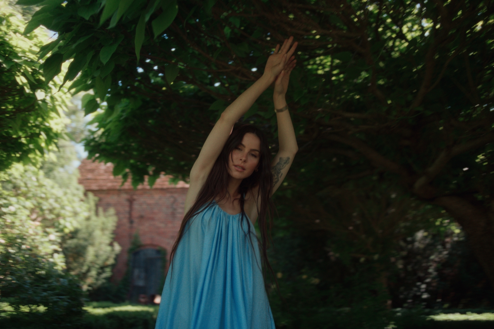 a woman in a blue dress standing under a tree