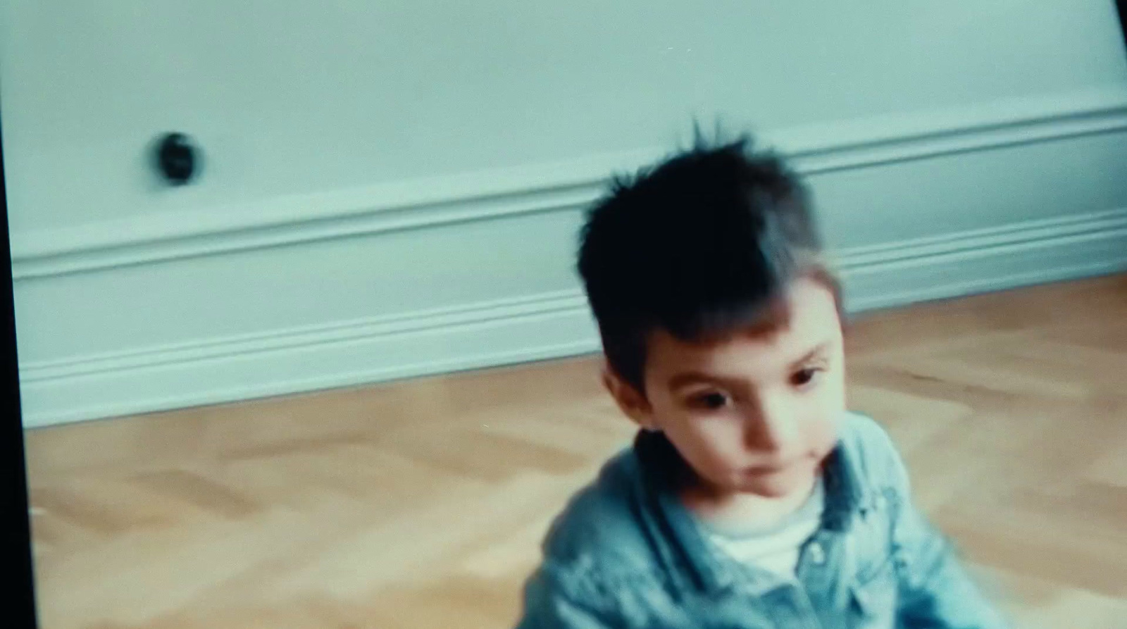 a young boy standing on a hard wood floor