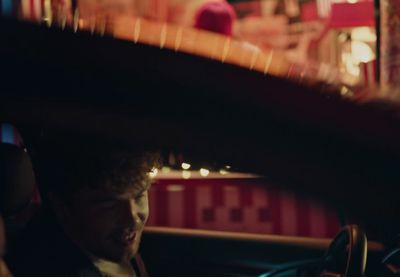 a young man sitting in a car looking at his cell phone