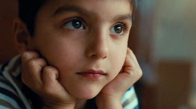 a young boy with blue eyes and a striped shirt