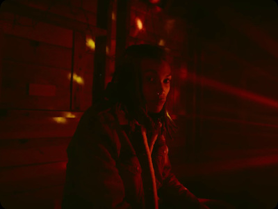 a woman standing in a dark room with a red light