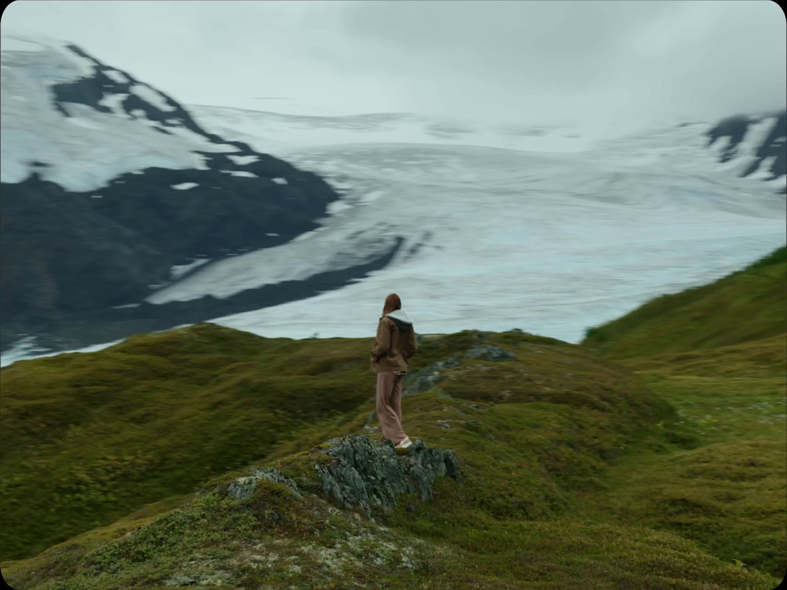 a woman standing on top of a lush green hillside