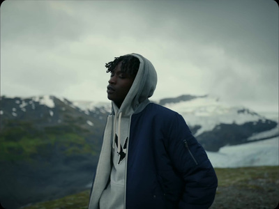 a man in a hoodie standing in front of a mountain