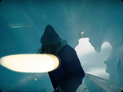 a person holding a surfboard in front of an ice cave